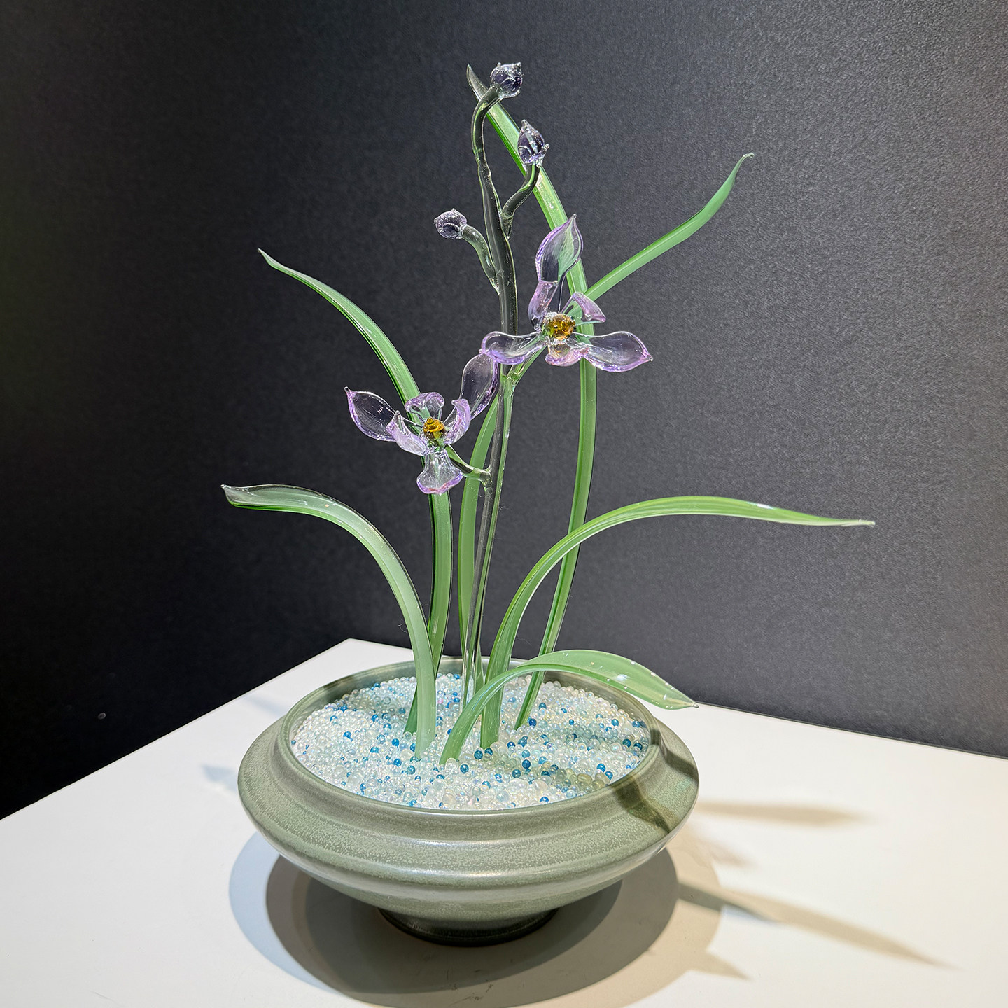 Blue-and-white seed beads settle the roots in ceramic